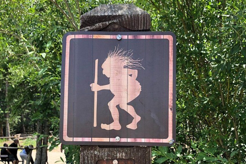 A sign with a silhouette of a person holding a staff, surrounded by greenery. 2