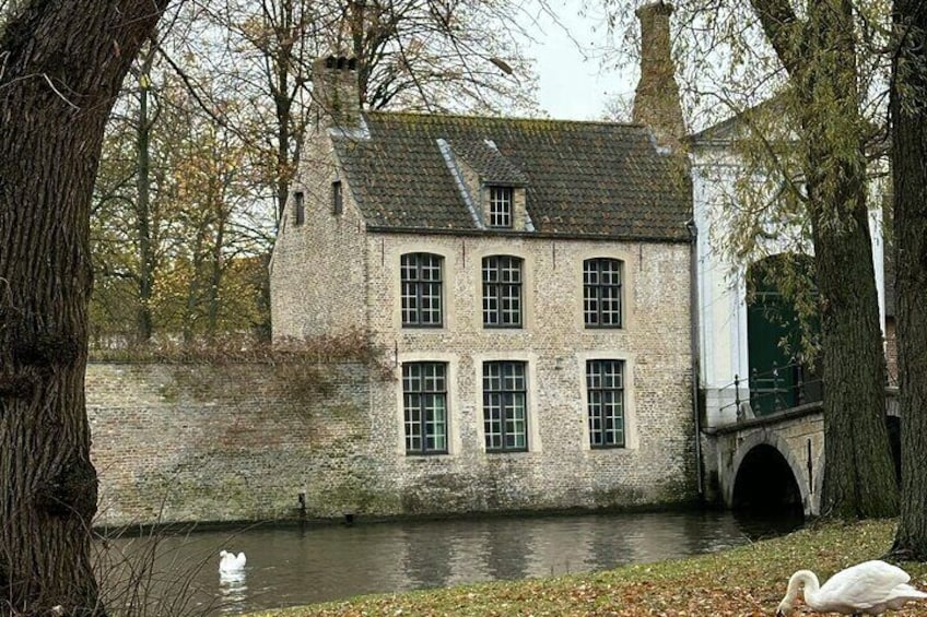 A stone building with multiple windows and a bridge over a canal. 4