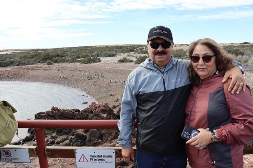 A couple standing by a rocky shoreline with a warning sign indicating a maximum capacity of 20 people. 4