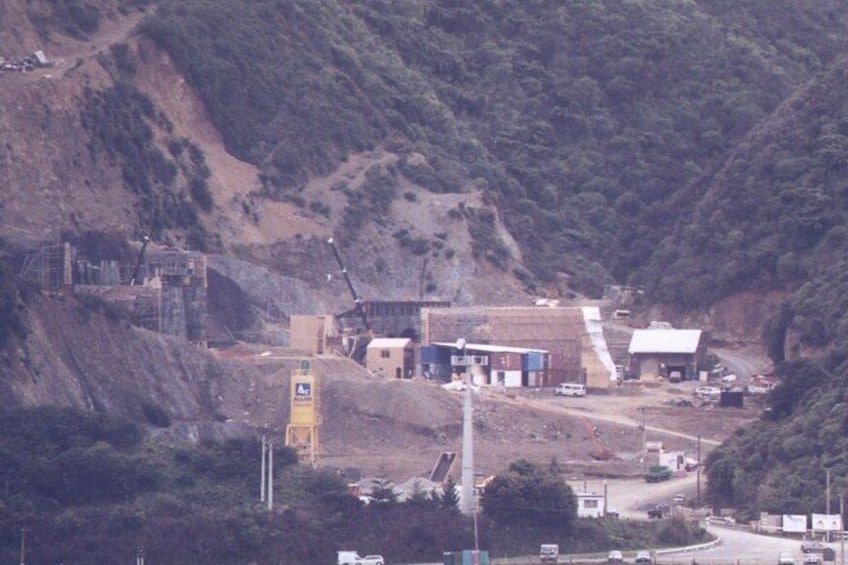 A construction site with buildings, a road, and a hilly landscape. 3