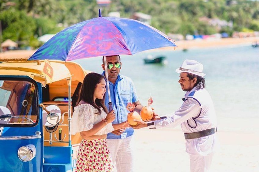 A tuk-tuk, a woman, and a man with an umbrella, and a person handing over coconuts. 3