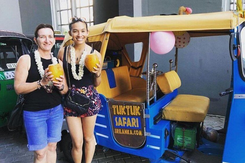 Two people standing next to a blue tuk-tuk with a sign that reads 'TUKTUK SAFARI'. 1