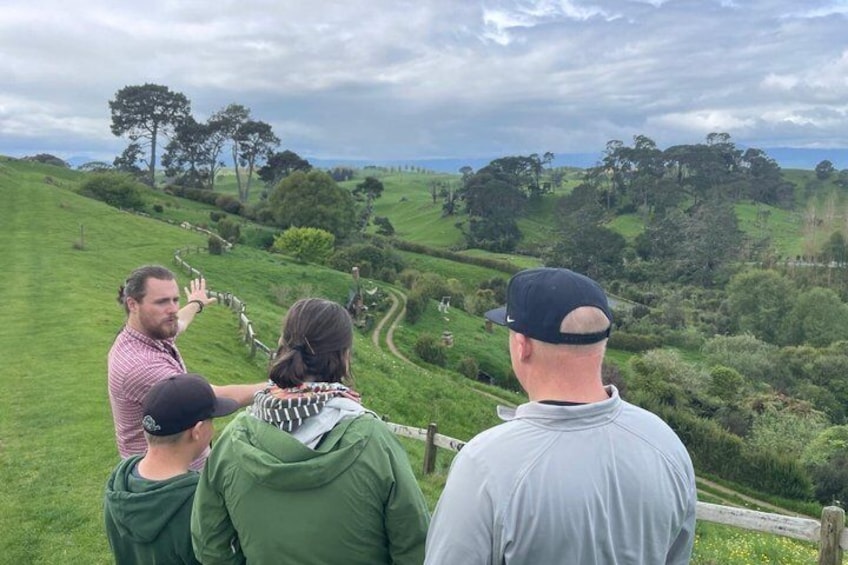 A group of people standing on a grassy hill overlooking a landscape with rolling hills and trees. 1