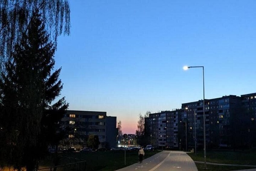 A sunset over a residential area with apartment buildings, a street, and a pedestrian. 3