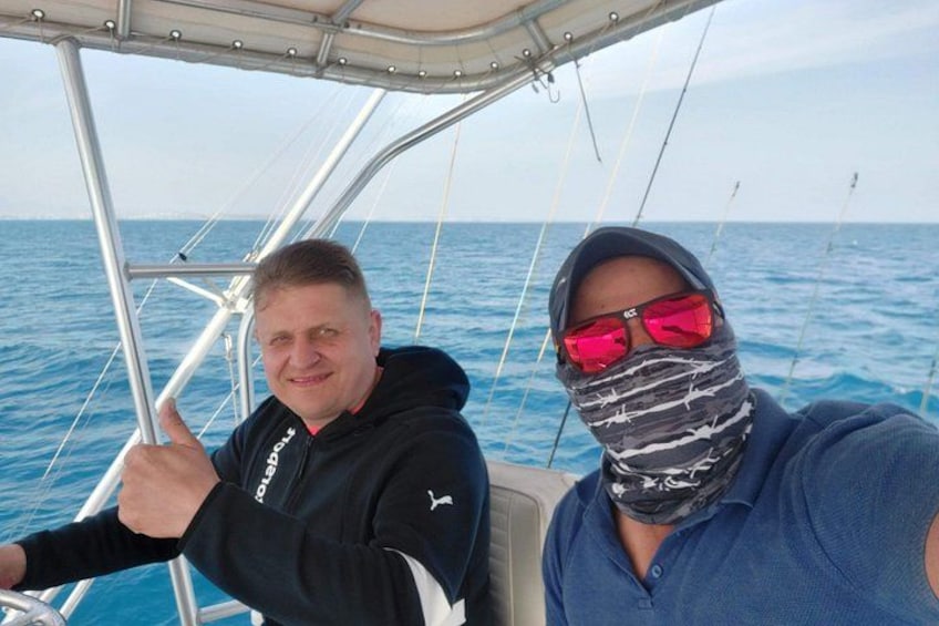 Two people on a boat with a clear blue sea in the background. 5