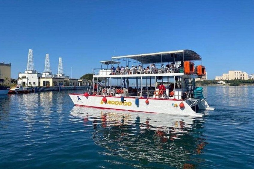 A boat with passengers, a clear blue sky, and industrial buildings in the background. 3