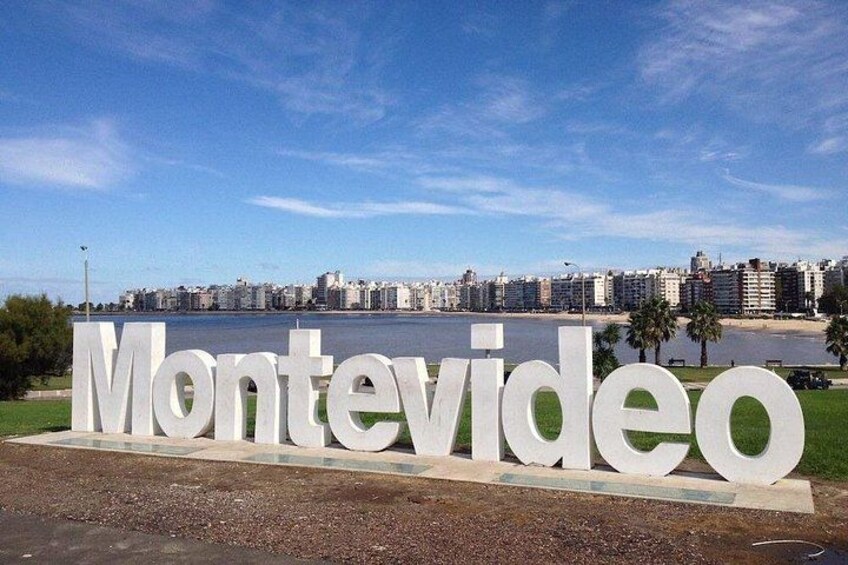 A large white sign with the text 'Montevideo' against a backdrop of a city skyline and a body of water. 3
