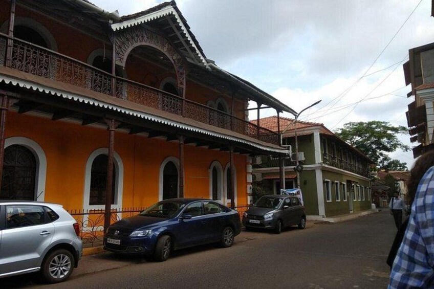 Una calle con coches aparcados, un edificio con balcones ornamentales y un edificio verde al fondo. 4