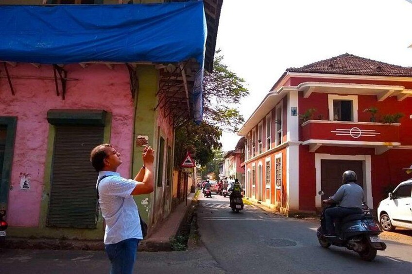 Una escena callejera con una persona tomando una foto, una moto y edificios de colores. 1