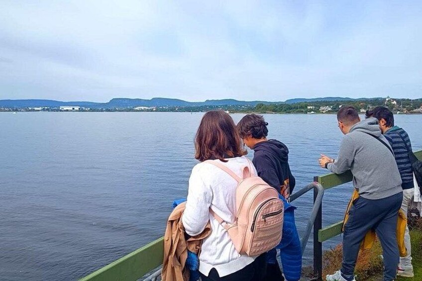 Un grupo de personas en un bote, observando un lago tranquilo con colinas al fondo. 4