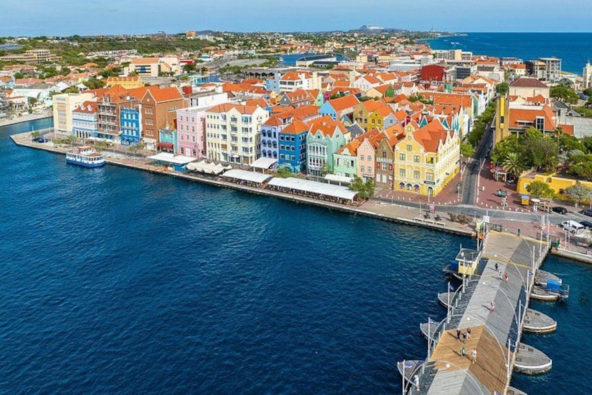 A coastal town with colorful buildings, a waterfront promenade, and a dock with boats. 3