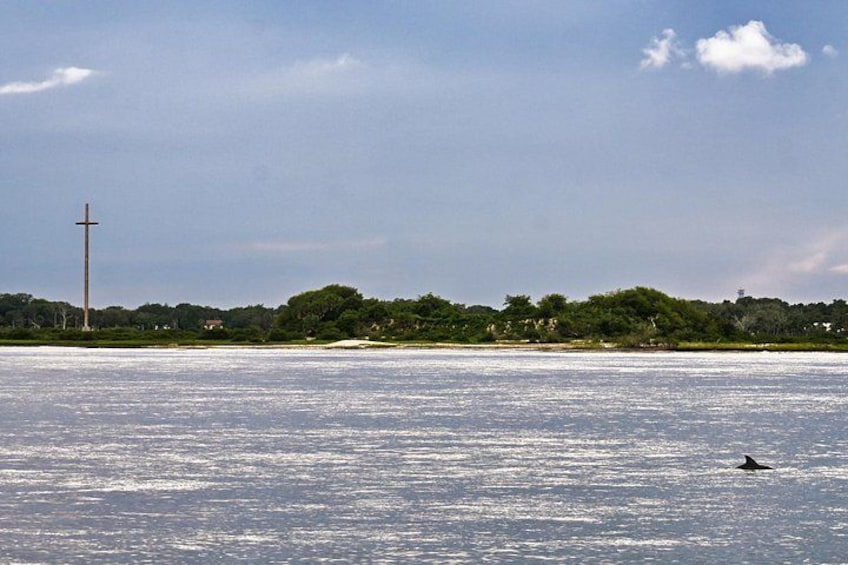Een rustig wateroppervlak met een kruis in de verte en iemand die zwemt. 2