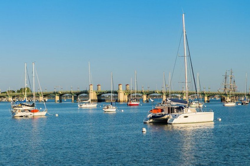 Een jachthaven met enkele zeilboten en een brug op de achtergrond. 4