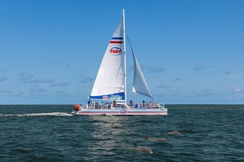 A sailboat with a white hull and blue accents, named 'FURY,' sailing on the ocean. 2