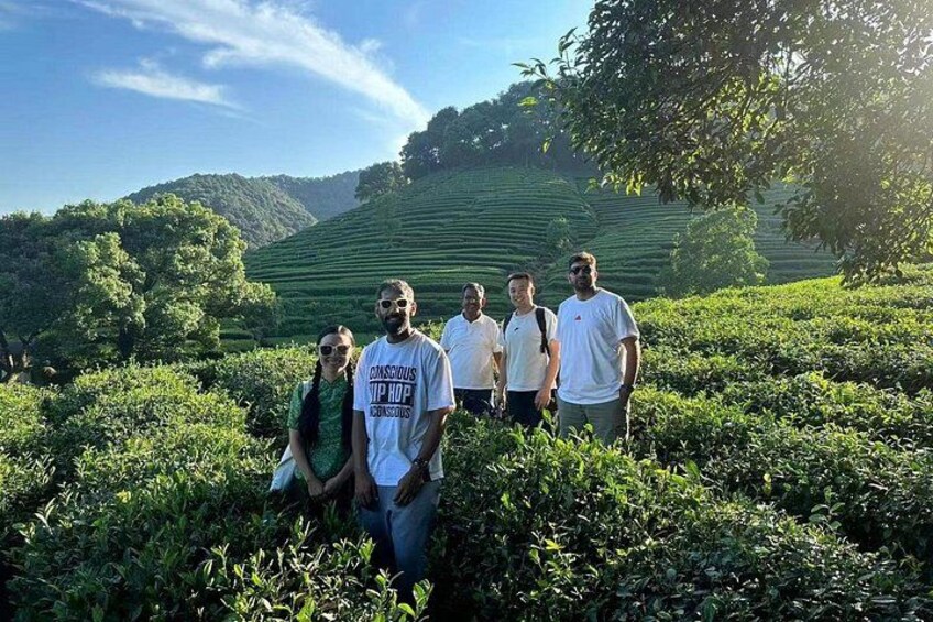 A group of people standing in a tea plantation with terraced hills in the background. 1