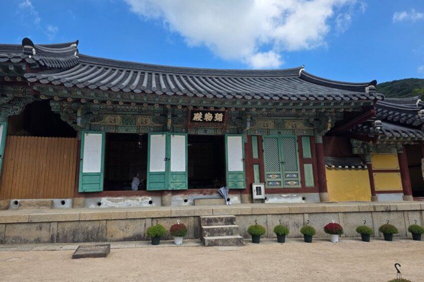 Een traditioneel Koreaans gebouw met groene en gele accenten, een betegeld dak en een bord met Koreaanse tekens. 4