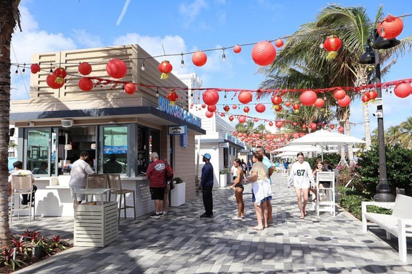 Una calle con un Burger King, palmeras y faroles rojos. 2