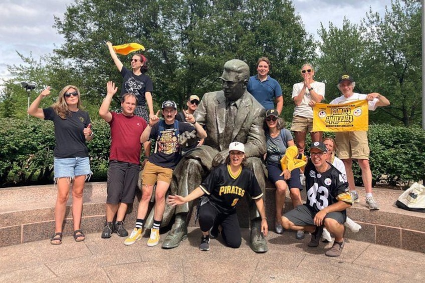 A group of people posing with a pirate-themed statue and holding a banner. 2