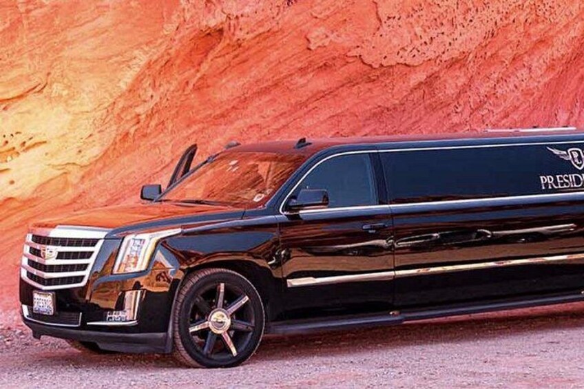En svart limousine med ordet ”PRESIDENT” skrivet på sidan, parkerad framför en röd klippformation. 1
