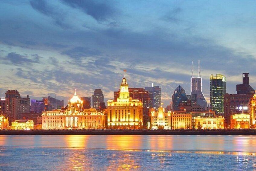A city skyline at dusk with illuminated buildings reflecting on the water. 5