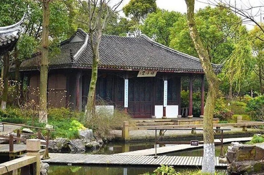A traditional Japanese building with a tiled roof, surrounded by trees and a pond. 1