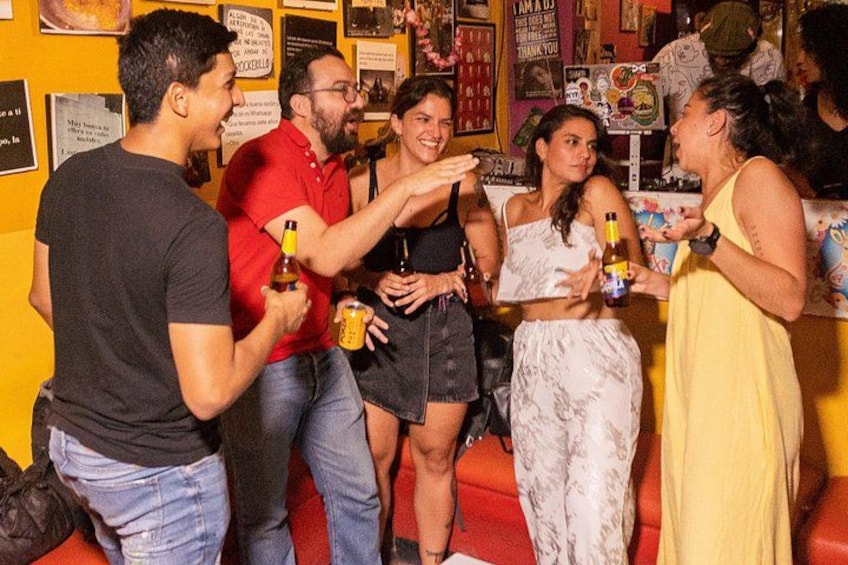 A group of people socializing in a bar with drinks. 2
