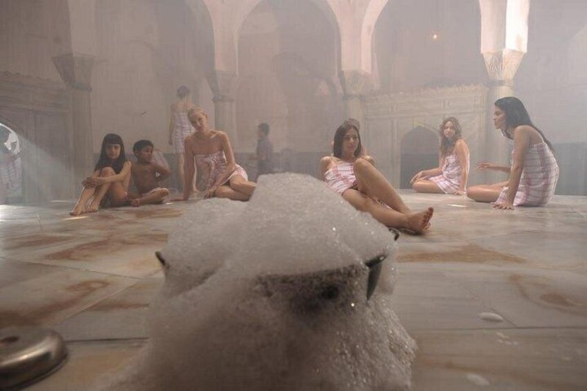 A group of people sitting on the floor in a large, open room with high ceilings and arches. 1