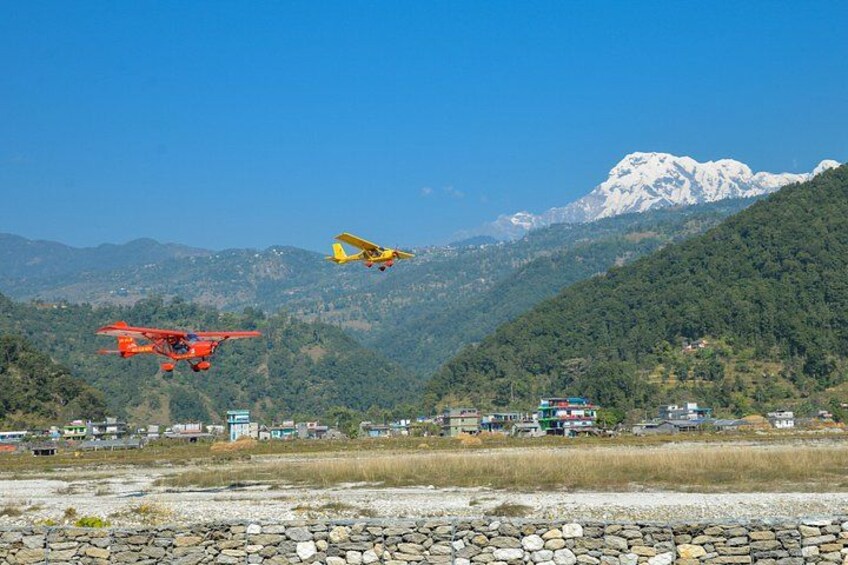 Two aircraft flying over a mountainous landscape with a clear sky. 5