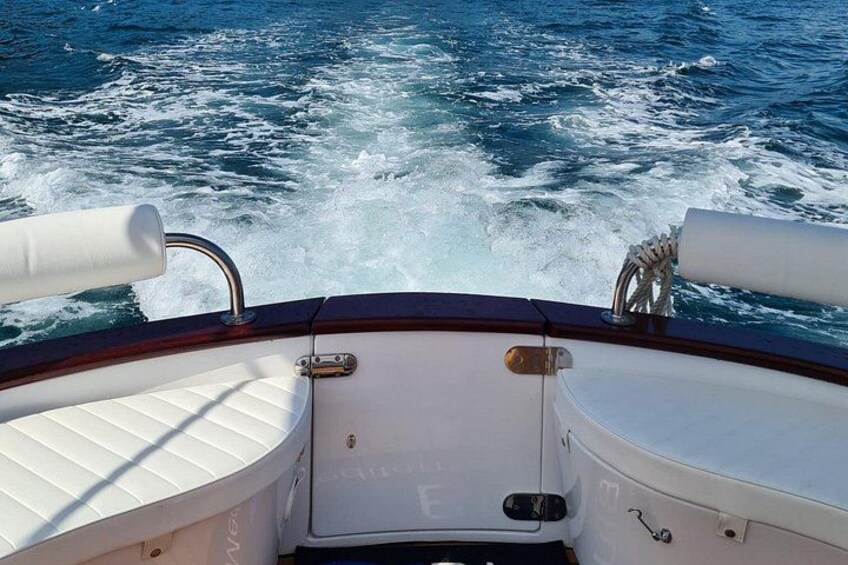 A boat's interior with a white cushioned seat and a metal railing. 4