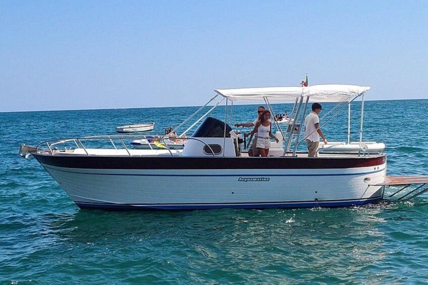 A boat with a white and black hull, a canopy, and people on board. 5