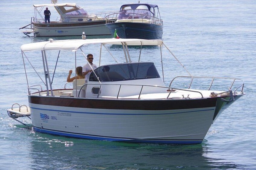 A small motorboat with two people on board, floating on calm water. 3