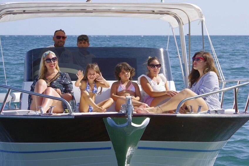 A group of people on a boat with a clear blue sky and calm sea. 1