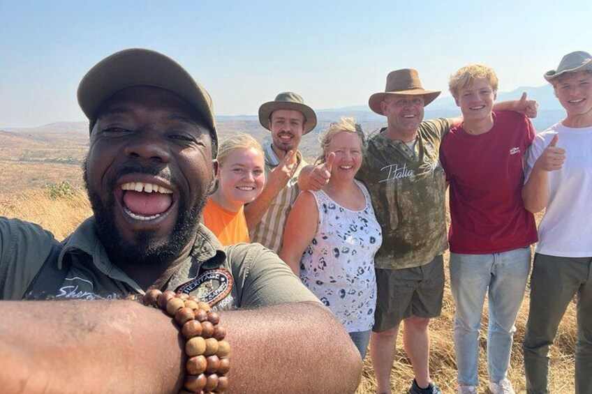 Un grupo de personas de pie al aire libre, con un paisaje montañoso de fondo. 3