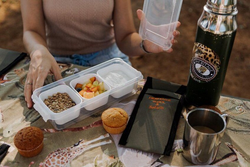 Una comida con un recipiente, una botella, un muffin y un libro sobre una mesa. 2