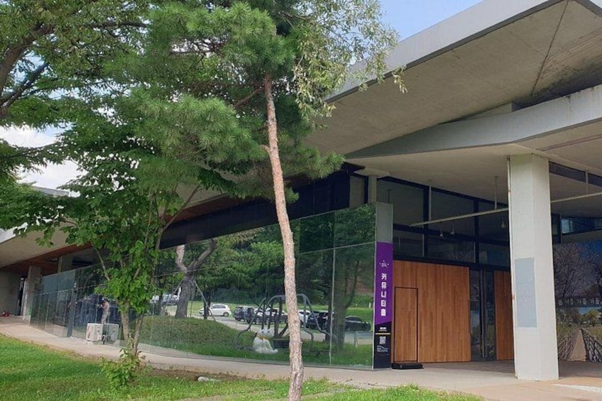 A modern building with a glass facade, a wooden door, and a tree in front. 2