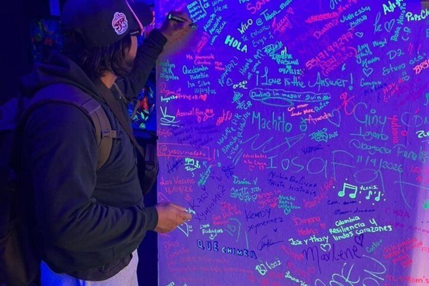 Une personne est en train d’écrire sur un mur recouvert de divers messages et dessins manuscrits. 5