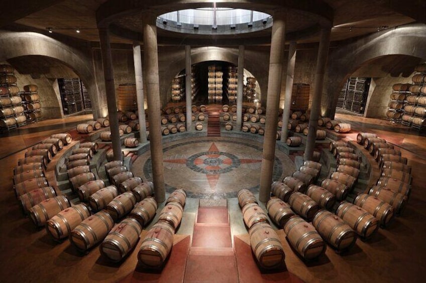 A circular room with wooden barrels arranged in concentric circles, a central circular platform, and a vaulted ceiling. 1