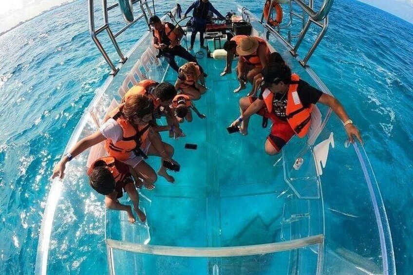People on a boat wearing life jackets, with clear blue water around them. 5