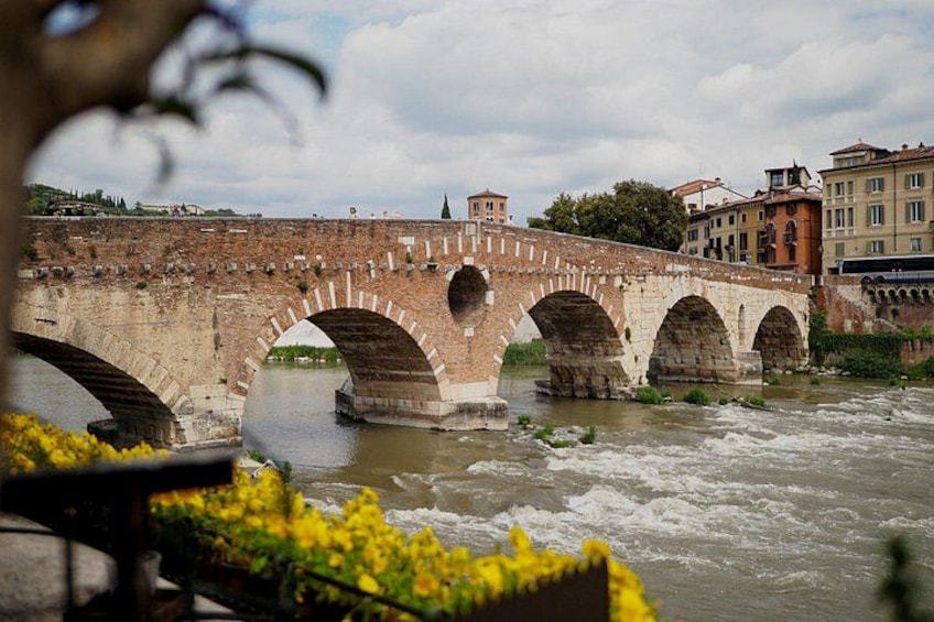 Un ponte in pietra con più archi che sovrasta un fiume, circondato da edifici e vegetazione. 1