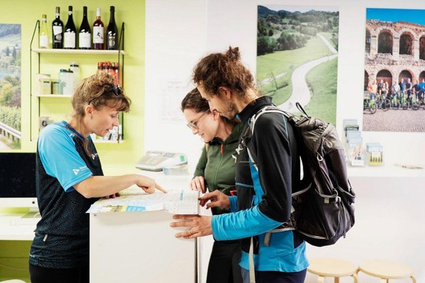 Tre persone al bancone con bottiglie di vino e una mappa. 5