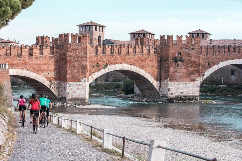 Un antico ponte in pietra con archi, un fiume e una struttura simile a un castello sullo sfondo. 2