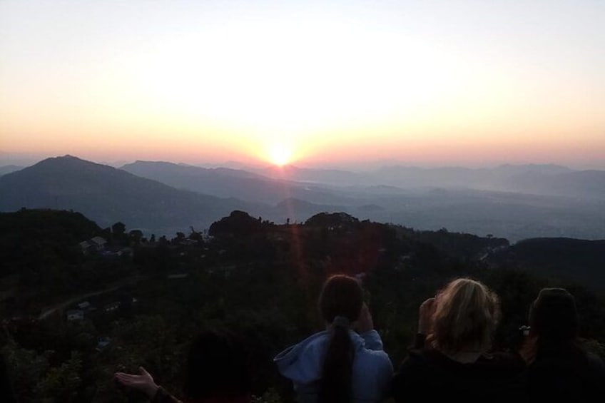 Atardecer sobre un paisaje montañoso con un grupo de personas contemplando la vista. 3