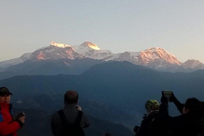 A group of people standing on a mountain ridge, overlooking a range of snow-capped peaks. 3