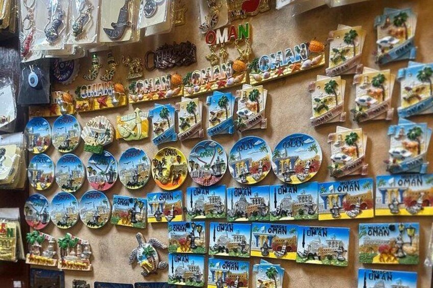 A wall covered with various souvenirs and postcards featuring Oman. 5