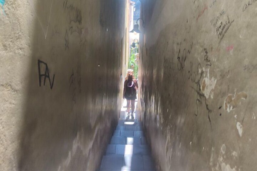 Een smalle steeg met graffiti op de muren, iemand loopt er doorheen. 3