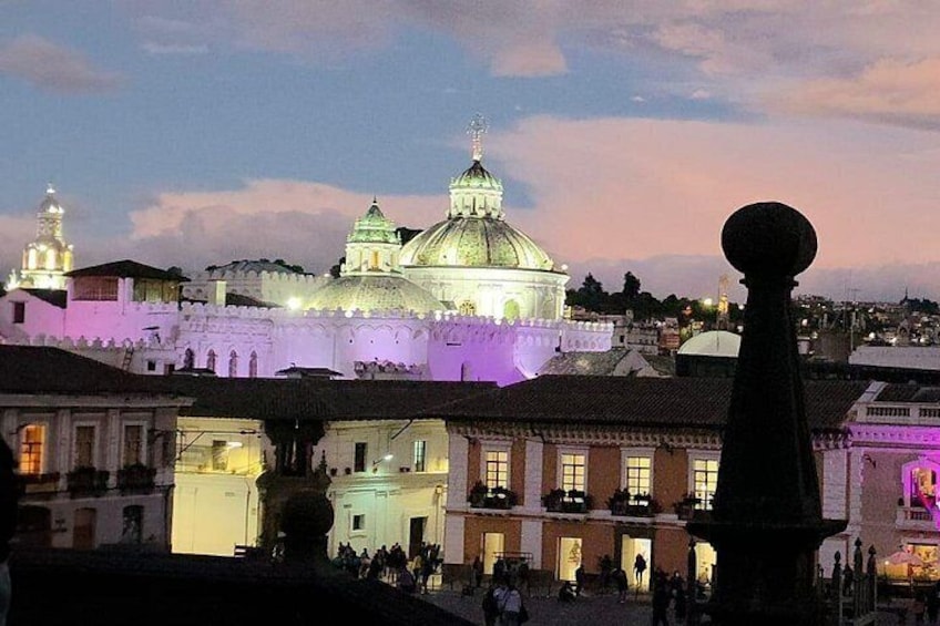 Un paisaje urbano al anochecer con edificios iluminados y una estructura de cúpula destacada. 2