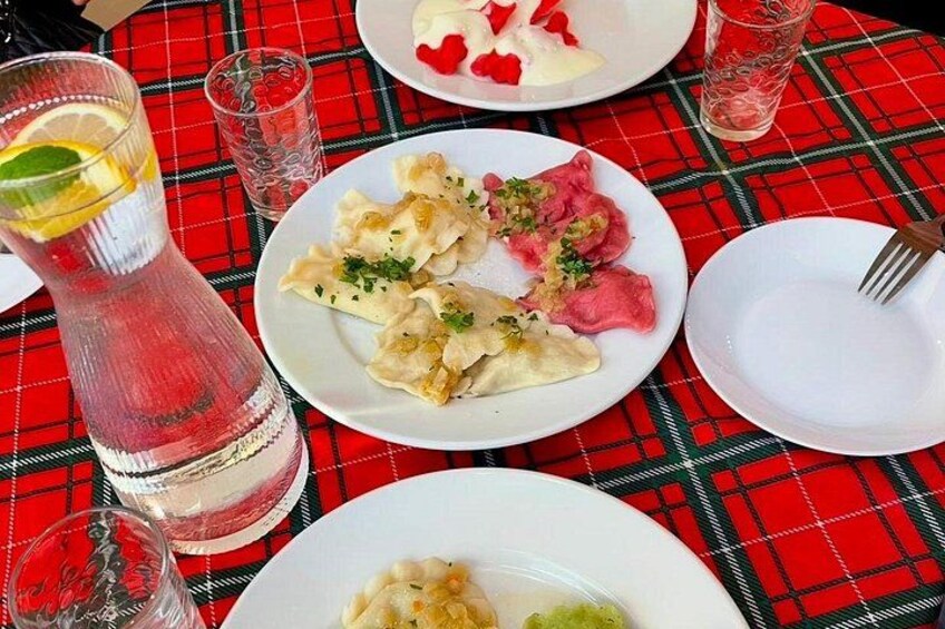 A table with a red and black checkered tablecloth, plates of food, and glasses of a pink beverage. 1