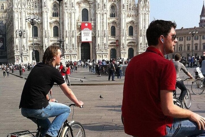 En person som cyklar framför en stor katedral, med en folkmassa i bakgrunden. 4