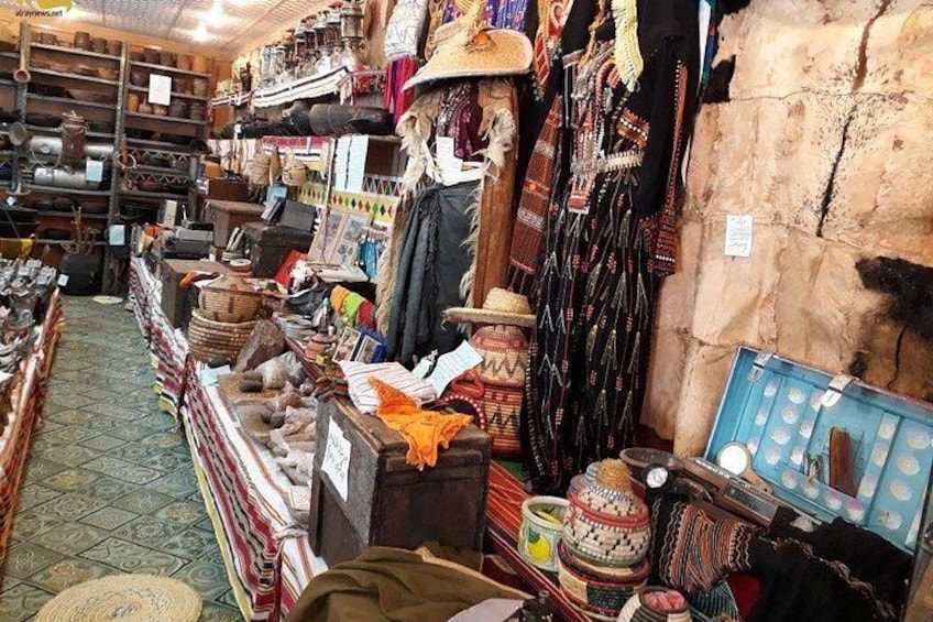 A market with various items on display including textiles, pottery, and shoes. 5