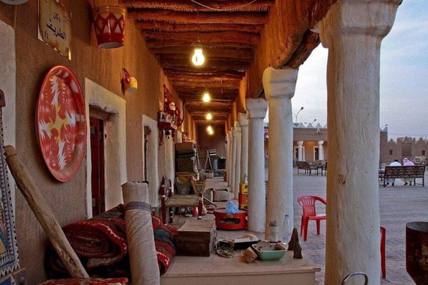 A covered outdoor seating area with traditional decor, including a patterned wall hanging and a wooden bench. 4